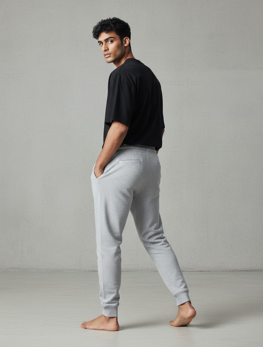 CosmoOtaku unisex grey melange cotton joggers with a tapered fit, ribbed cuffs, and back pocket detail on a model.
