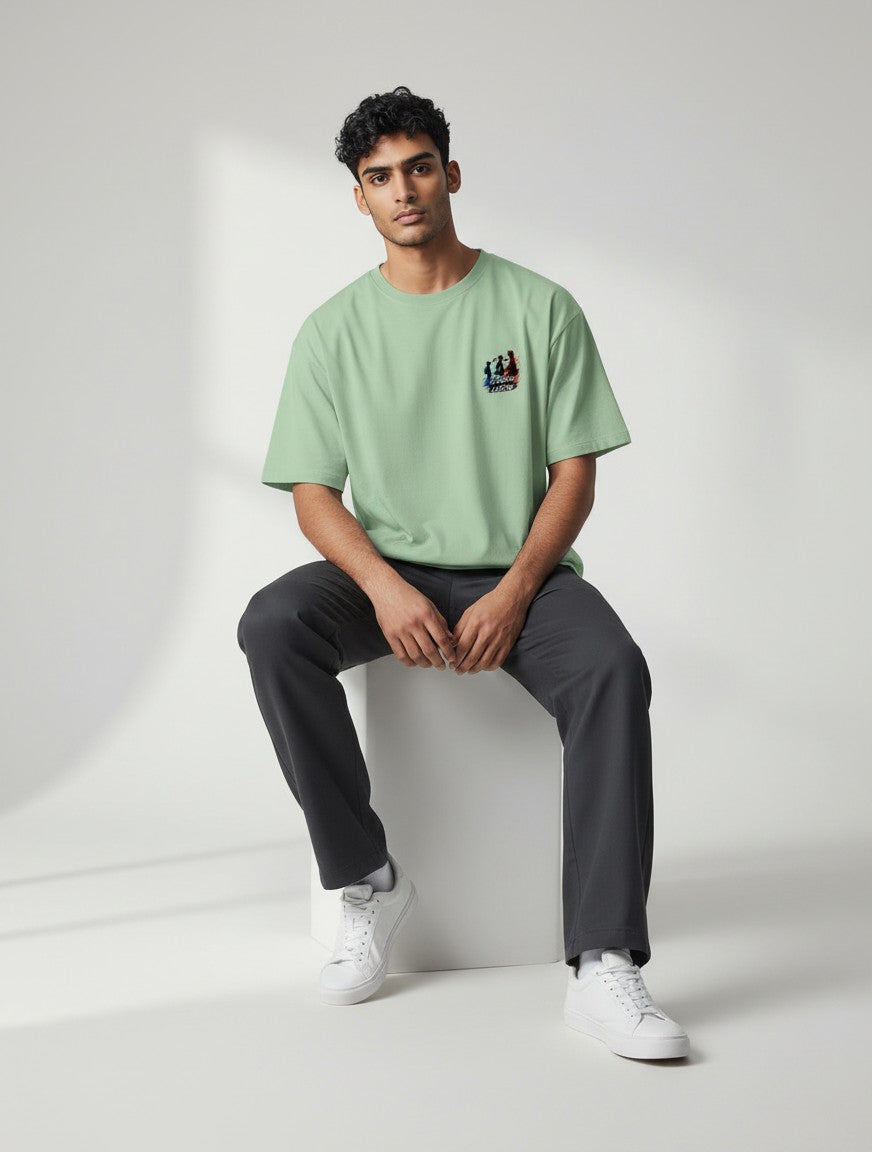 CosmoOtaku jade green unisex crew neck t-shirt with anime chest graphic, worn by a man sitting on a white block.