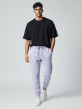 Model wearing CosmoOtaku lavender 100% cotton joggers with a tapered fit, drawstring waist, and ribbed cuffs.