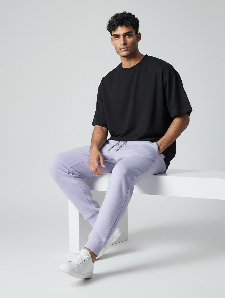 CosmoOtaku unisex lavender cotton joggers with a tapered fit and ribbed cuffs worn by a man sitting on a bench