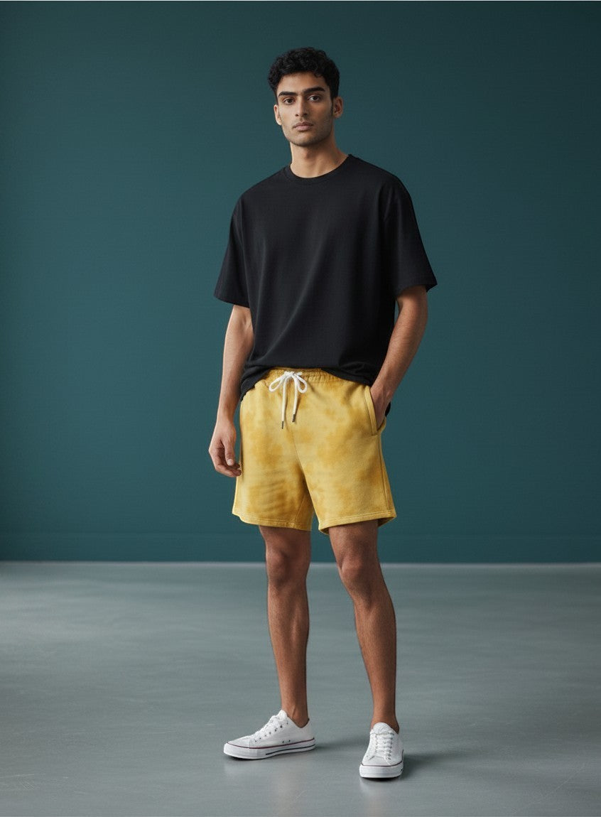 CosmoOtaku mustard yellow sun-washed drawstring shorts worn by a man with a black t-shirt and white sneakers