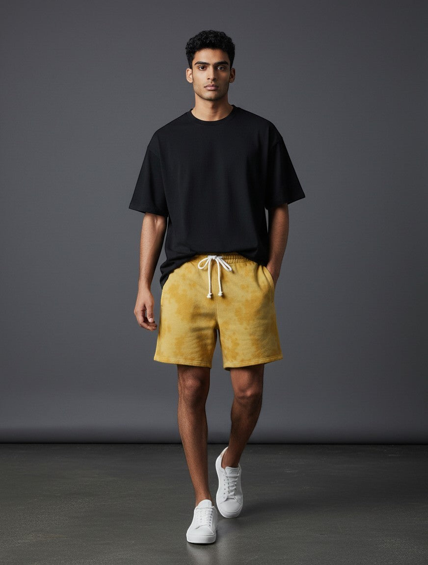 CosmoOtaku mustard yellow sun-washed drawstring shorts worn by a man with a black t-shirt and white sneakers