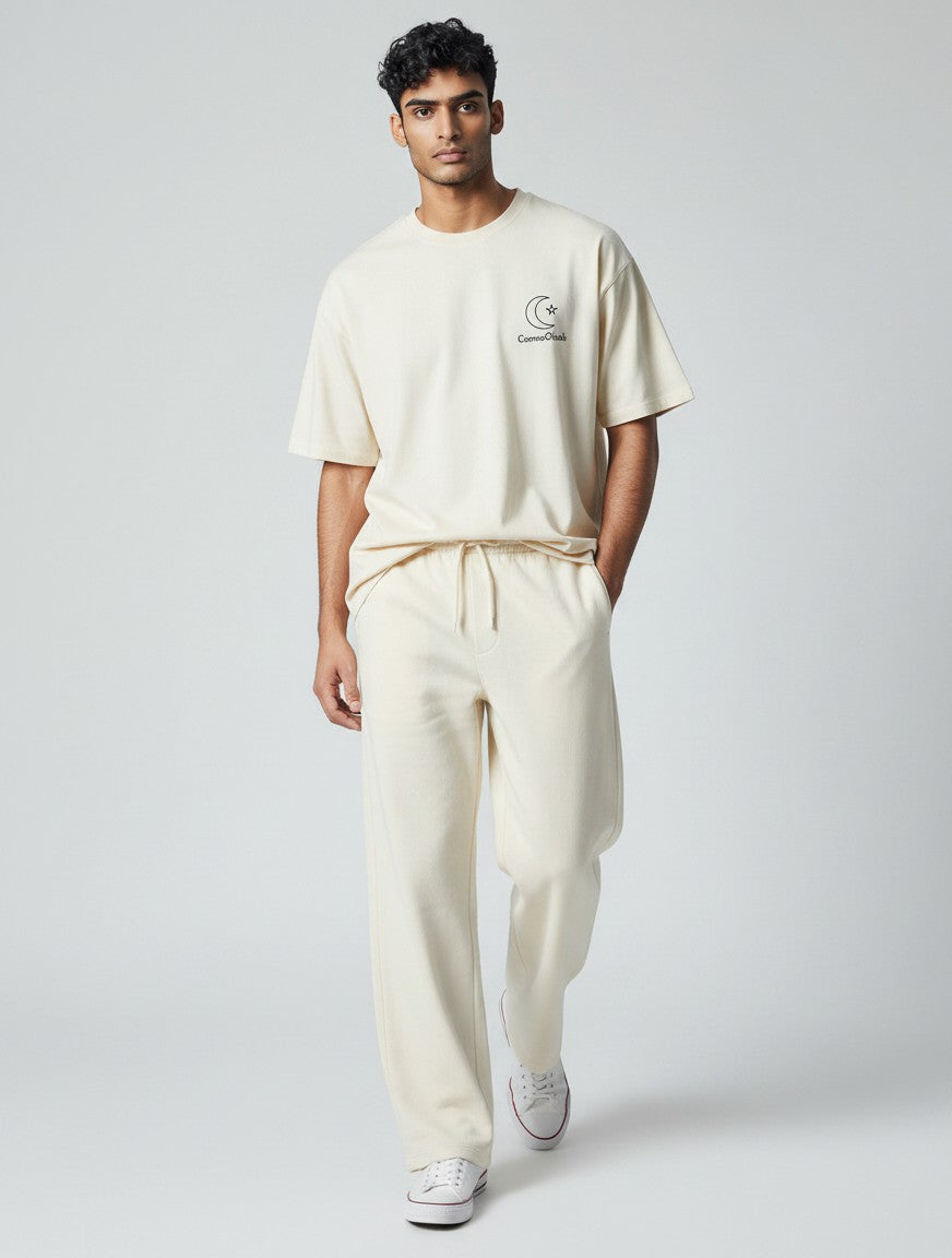 CosmoOtaku model wearing off-white loose-fit cotton terry sweatpants and matching t-shirt in a studio setting.