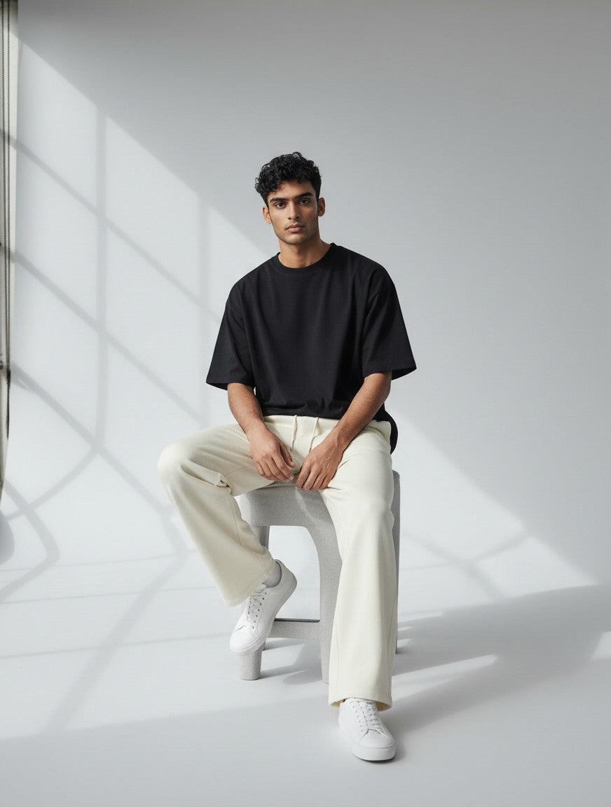 CosmoOtaku model wearing off-white loose-fit cotton terry sweatpants with a black t-shirt in a studio setting.