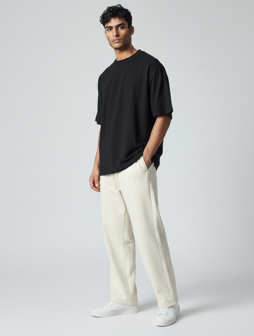 CosmoOtaku model wearing off-white loose-fit cotton terry sweatpants with a black t-shirt and white sneakers