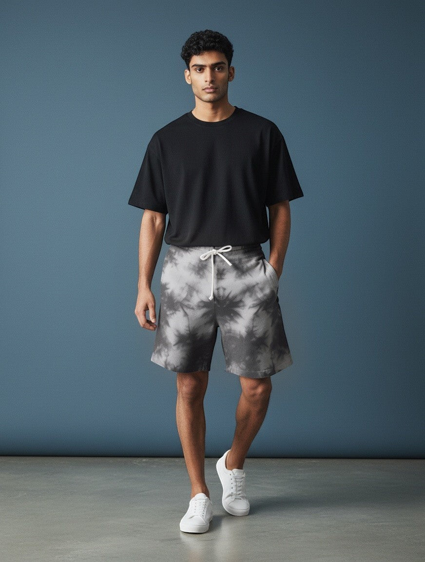 Model wearing CosmoOtaku grey and white tie-dye drawstring lounge shorts with a black t-shirt and white sneakers.