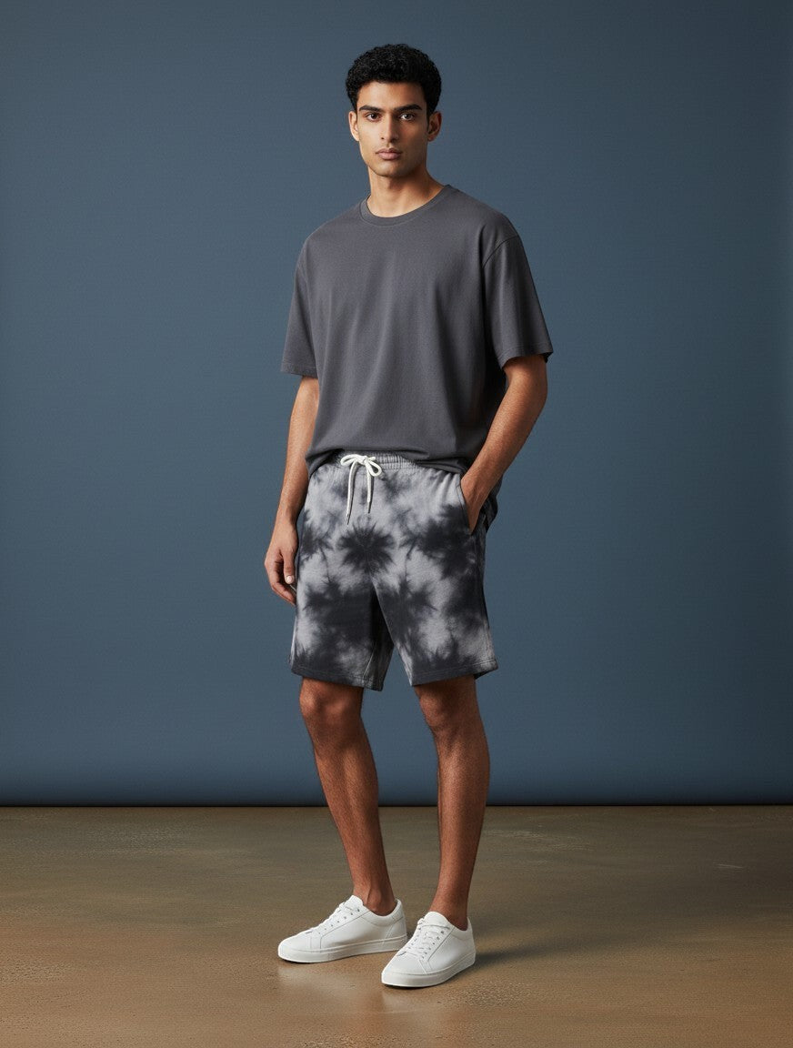 Model wearing CosmoOtaku black and white tie-dye drawstring lounge shorts with a grey t-shirt and white sneakers.